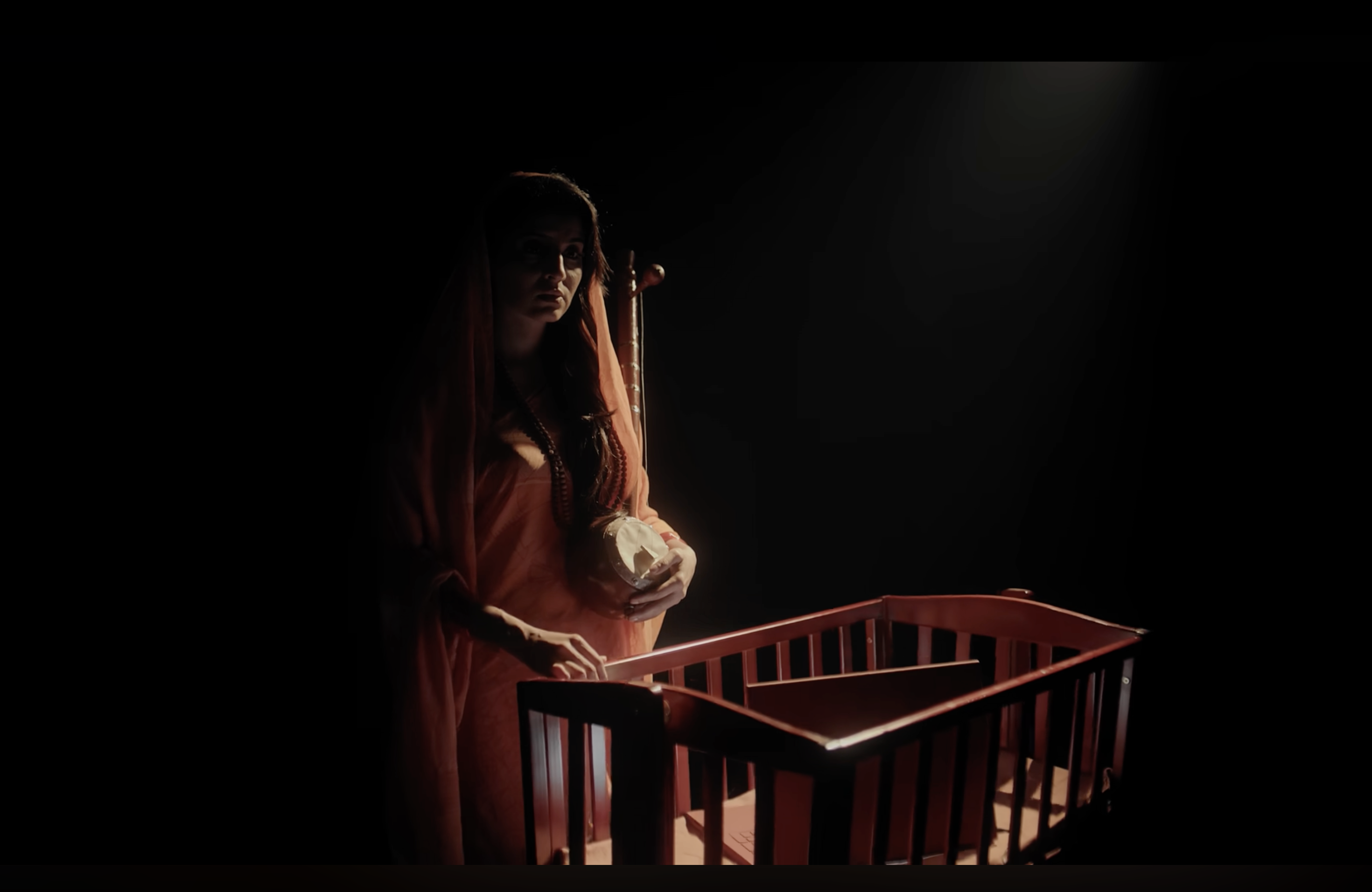 Kaahe Jaage Mohan: A woman beside a cot in low light
