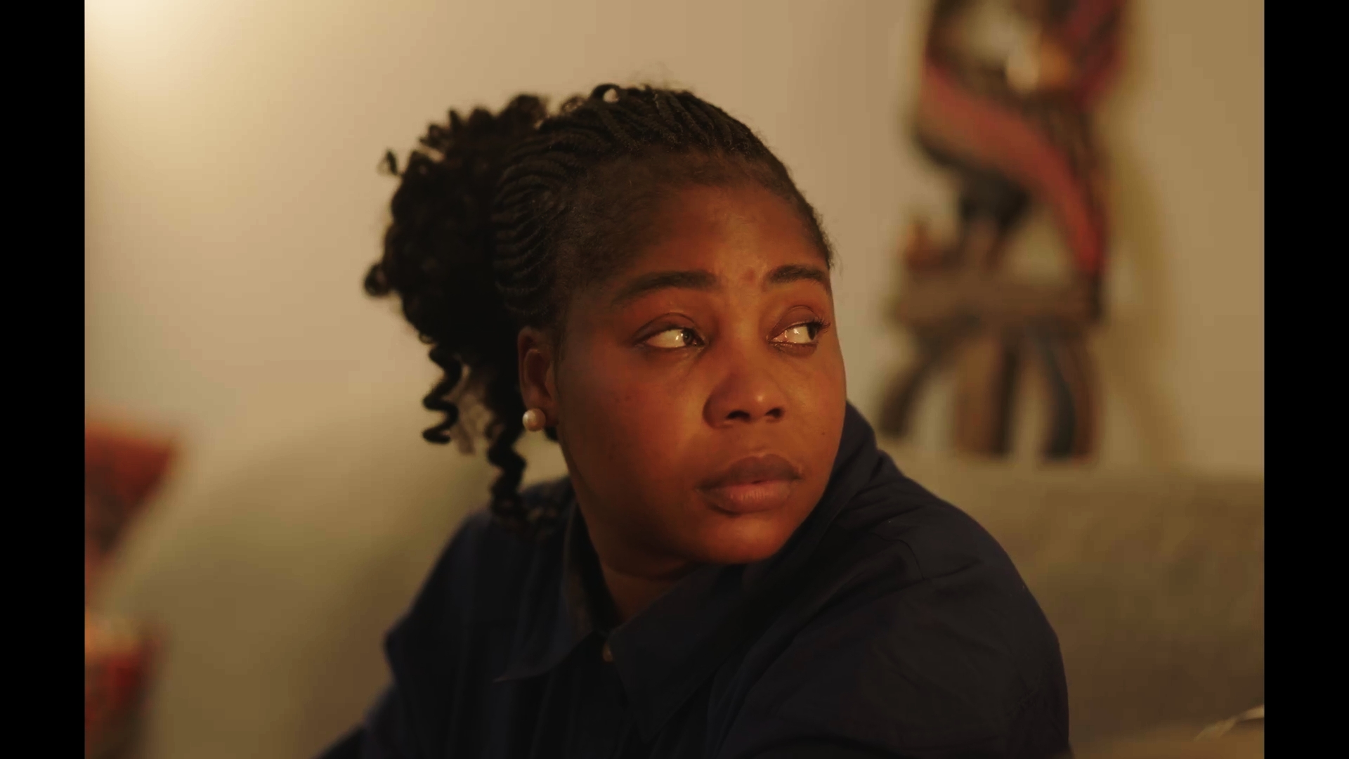Unbecoming / Serwaa: A woman seated in a living room