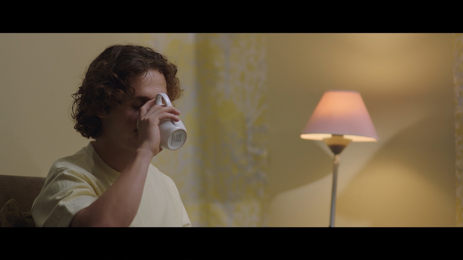 Between Worlds: A man holding a glass in a warmly lit room