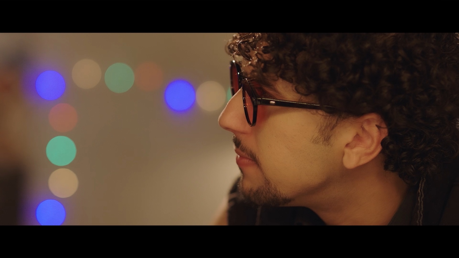 Between Worlds: A man wearing glasses in a bar