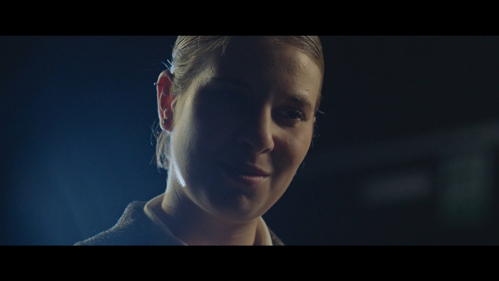Between Worlds: Close-up of a woman in a dark room