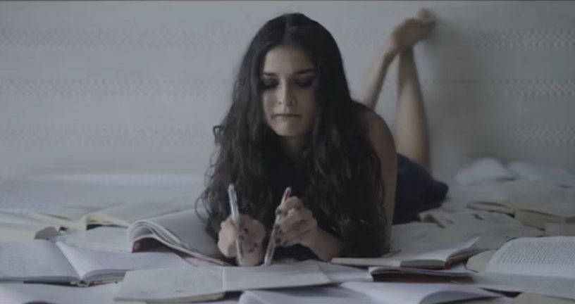 Entrapment: A woman writing among books on a bed
